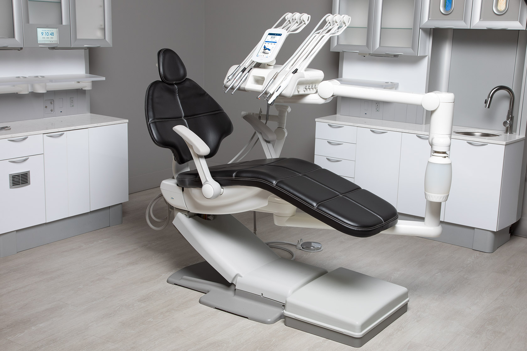 Dental chair with black upholstery, delivery system, and covered A-dec Maintain floor box in a dental operatory